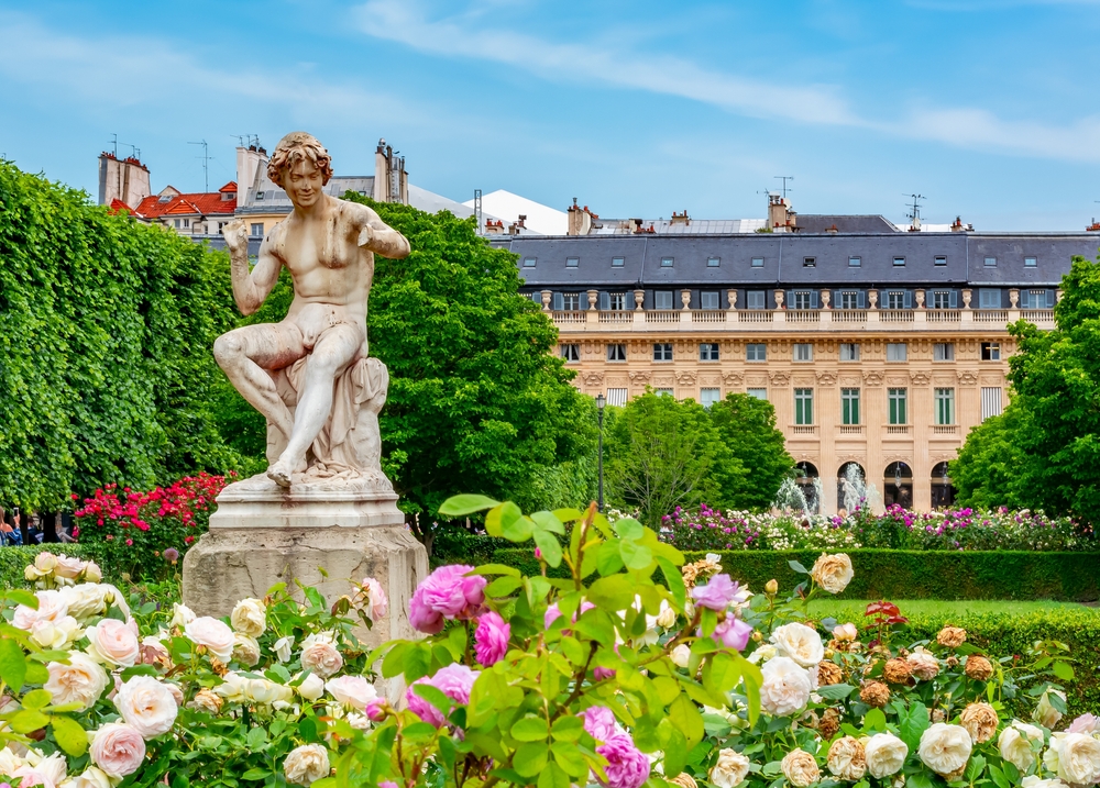 A stature of a man among flowers in the Jardin du Palais Royal.