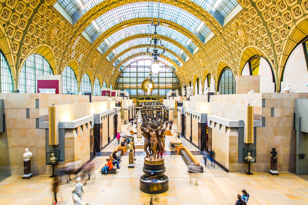 Inside the Musee d'Orsay with statues and people walking around.