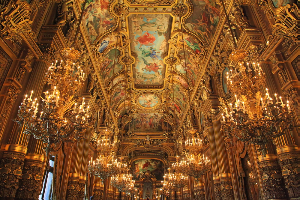 Intricate golden and painted ceiling with hanging chandeliers in Opera Garnier.