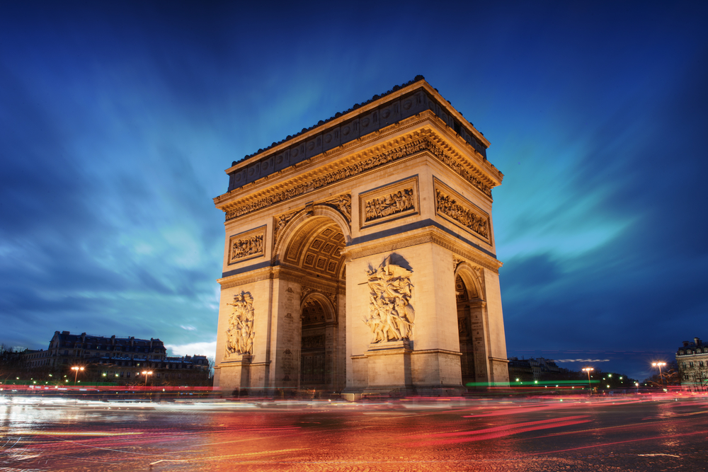 Arc de Triomphe Paris city at sunset. There are blurred lights at the bottom. 