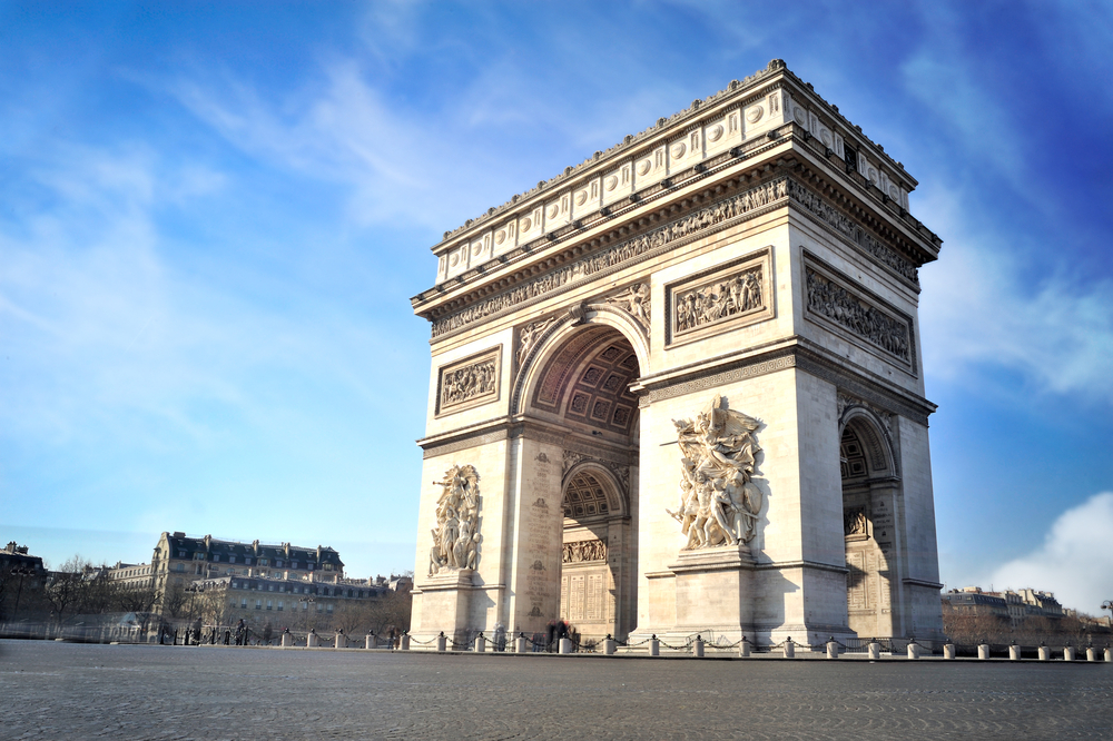 Sunny day over the white and detailed Arc De Triomphe in Paris.