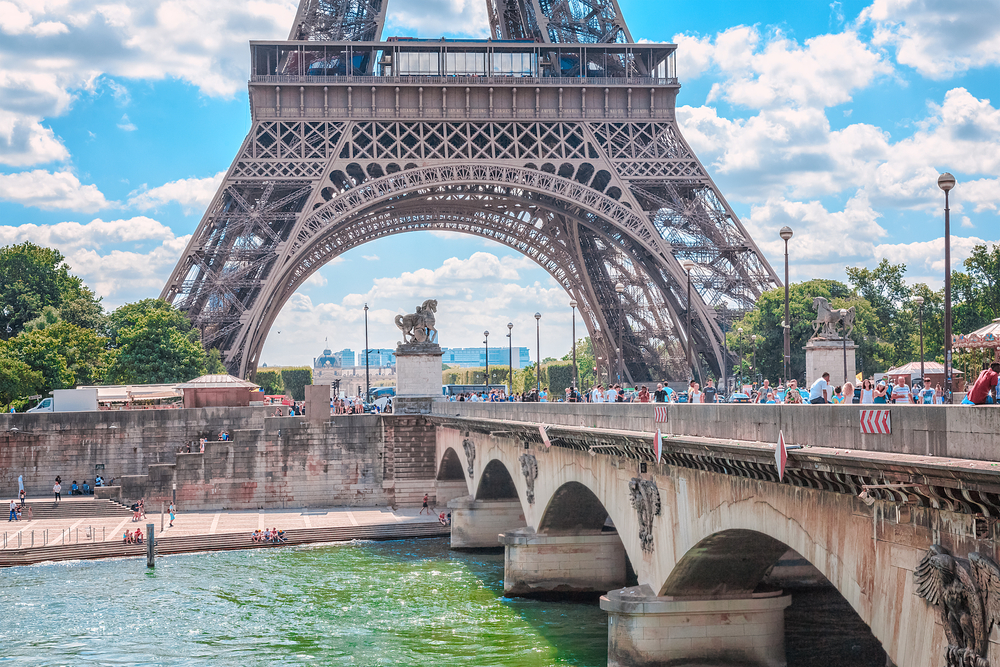 Opulent bridge with archways in forefront and Eiffel Tower in background. Bridges in Paris