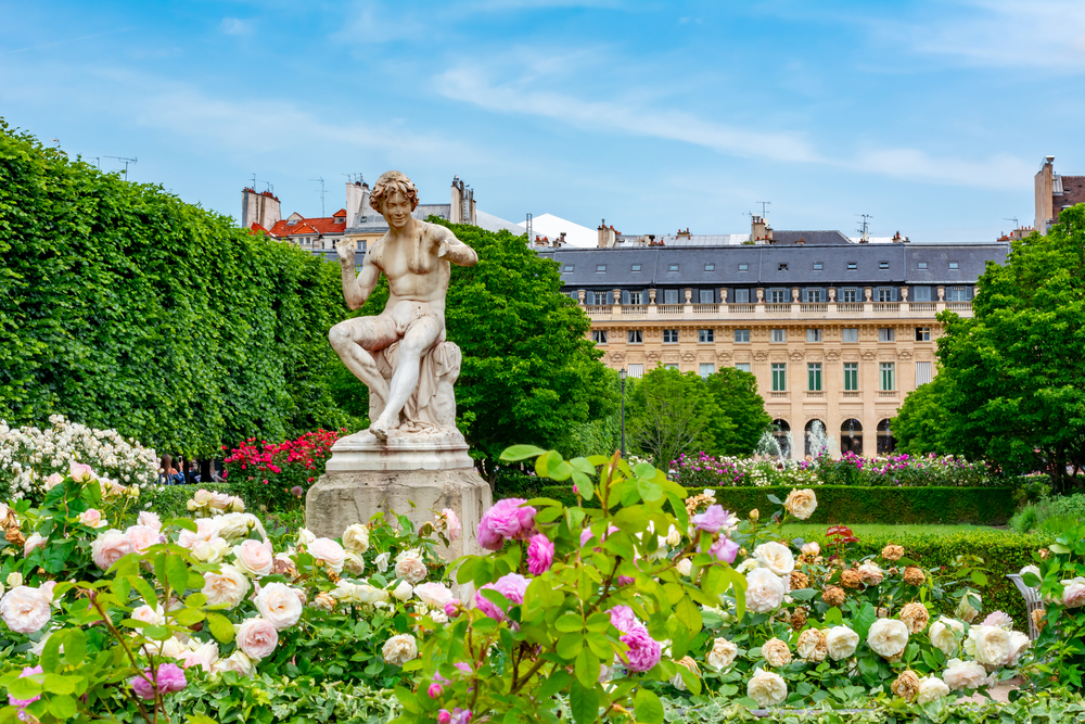 A sculpture among colorful flowers in the Jardin du Palais Royal during a London-Paris itinerary.