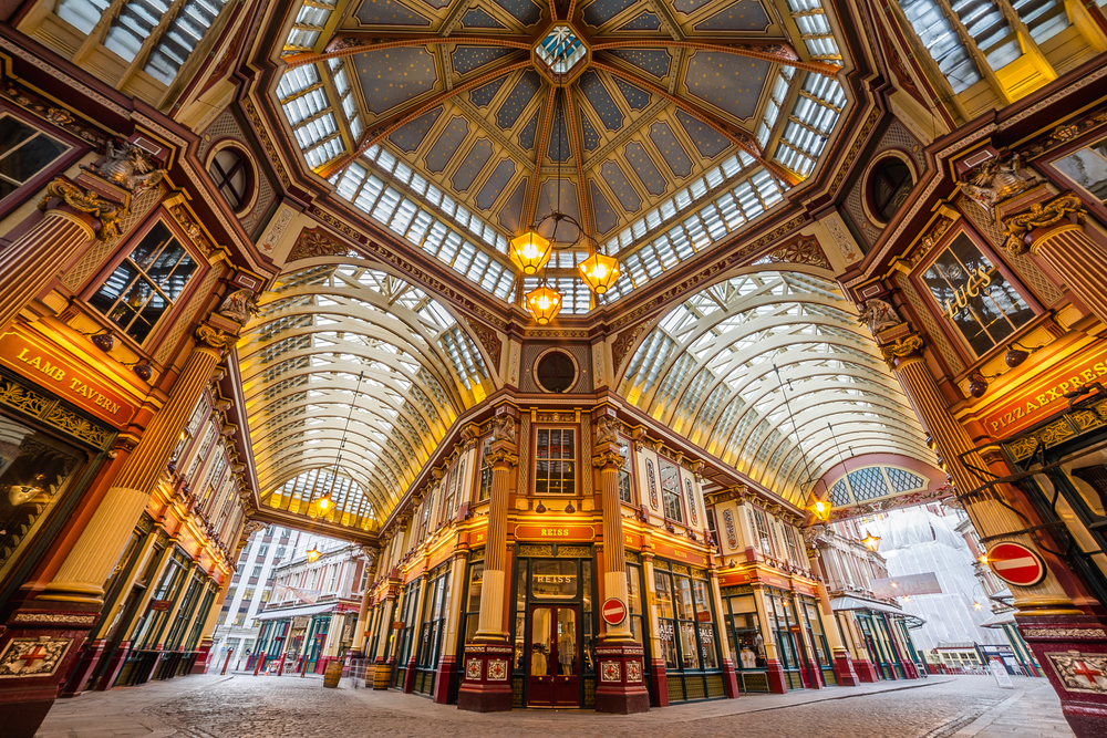 Wide-angle photo of Leadenhall Market lined with shops and a glass ceiling.
