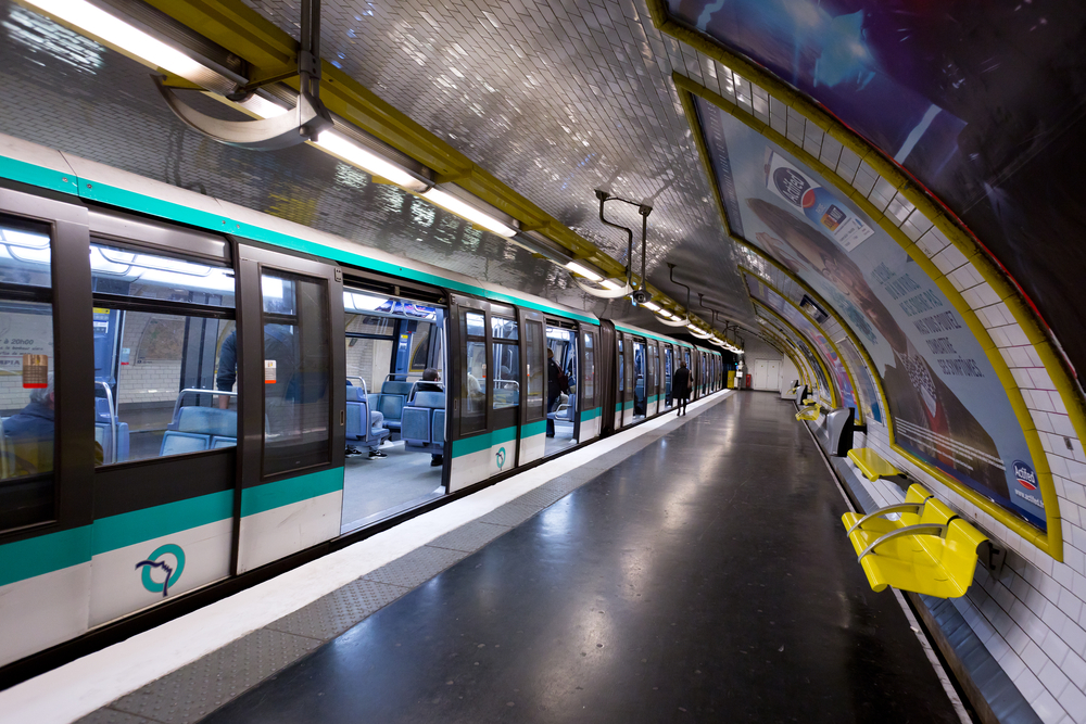 A metro train at the station in a tunnel with open doors on a London-Paris itinerary.