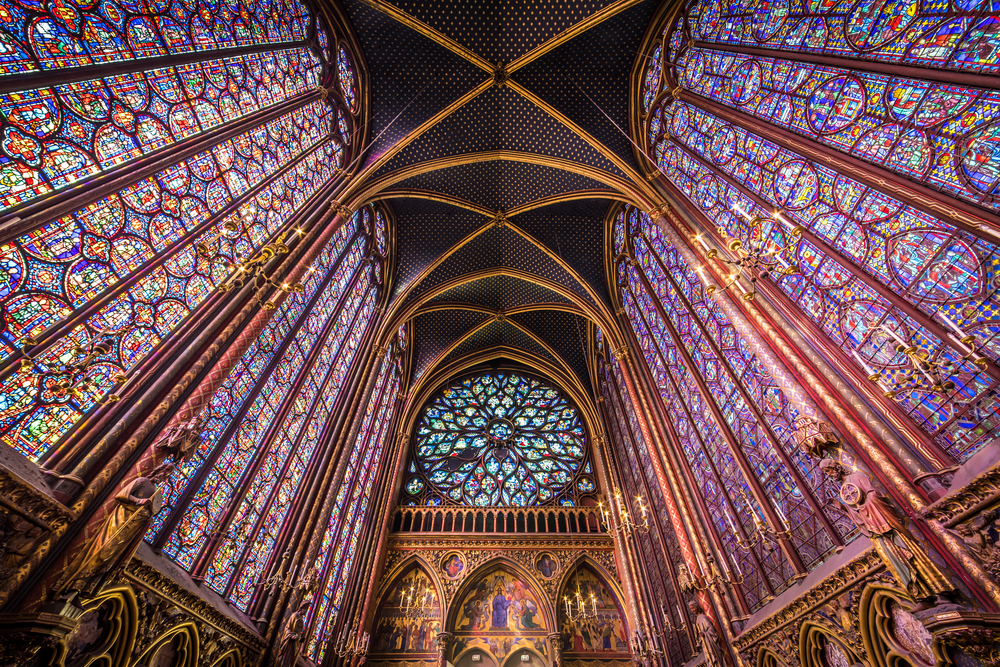 Looking up at the domed ceiling; purple and blue stained glass windows; and rose window inside the Sainte Chapelle church.