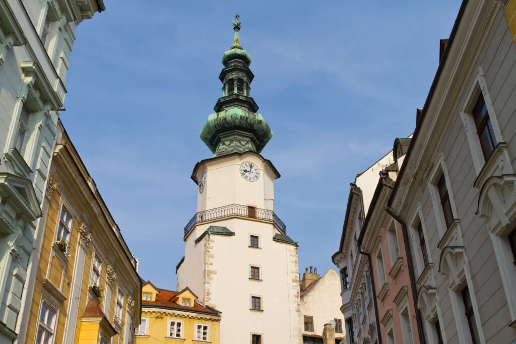 White tower with green dome center and colorful ornate buildings on either side