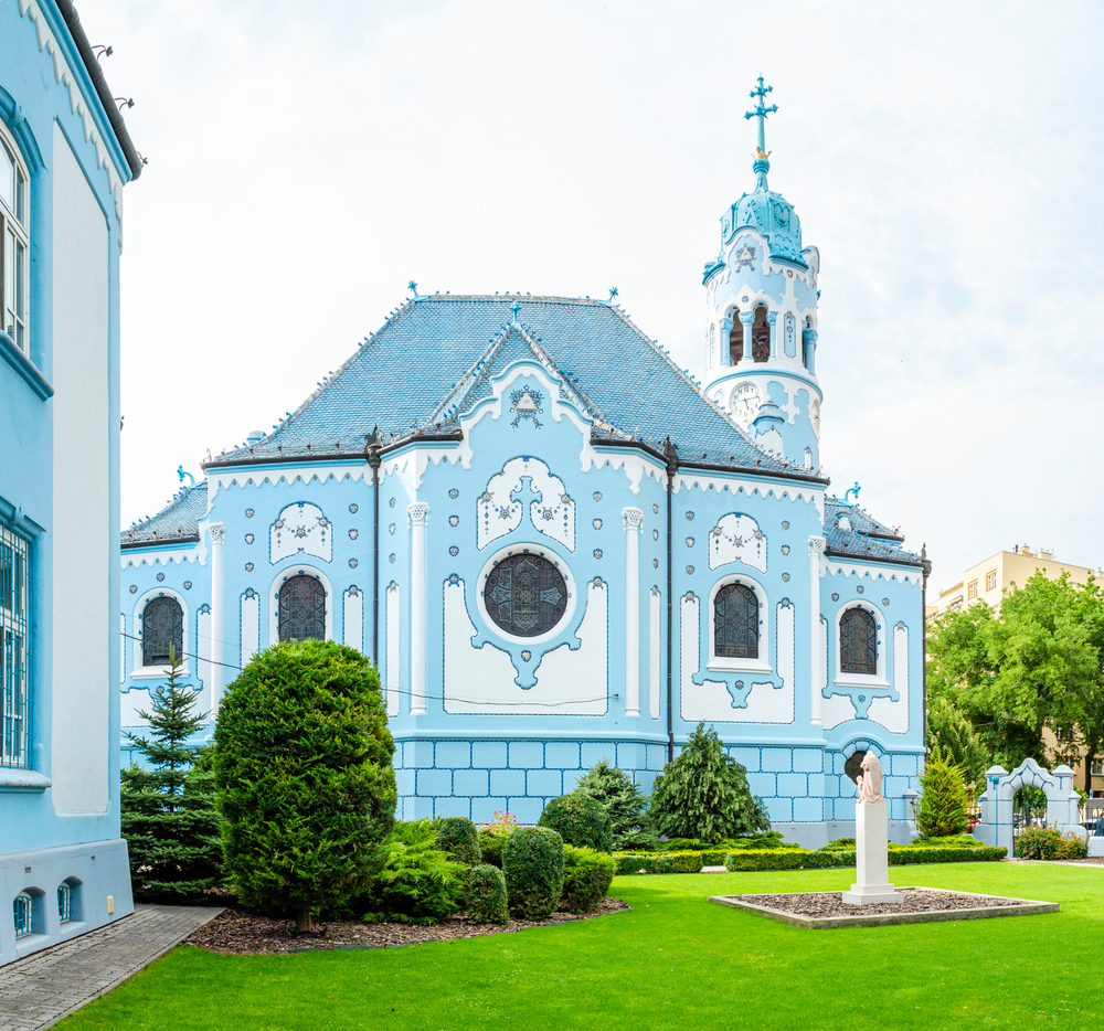 Ornate Blue church with blue tower. Green grass in foreground.