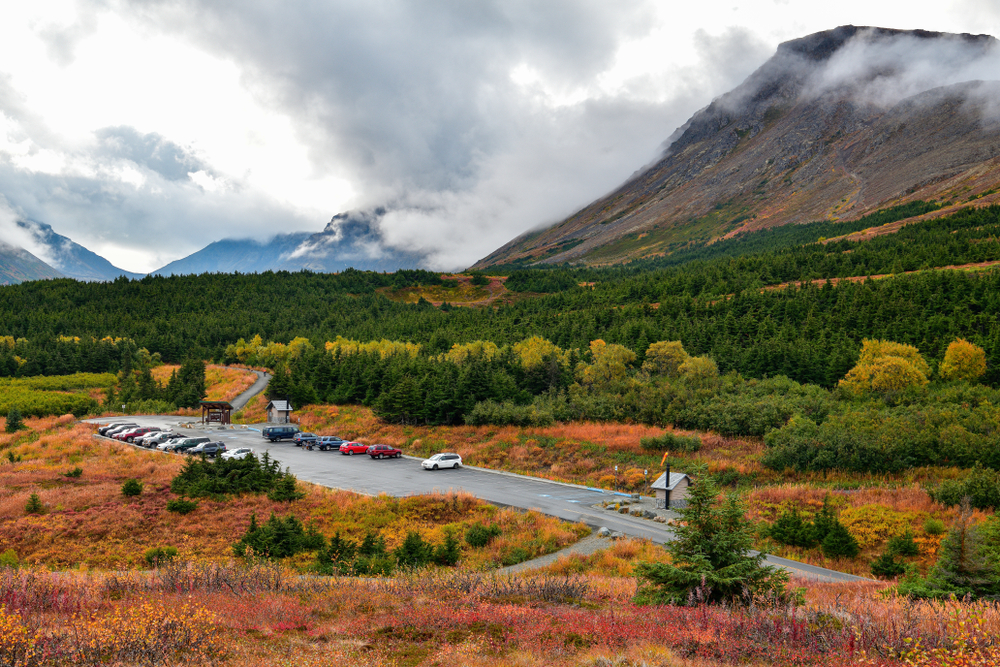 Fall colors at Flattop mountain in Anchorage. You can see a car park with the mountain above. The article is about hiking in Alaska.  