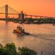 boat on a river with a bridge with the orange sky romantic getaways in the USA