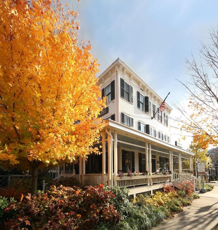 White colonial style hotel with fall foliage around. The hotel has a large deck. 