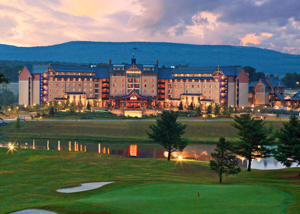 Large hotel complex behind a lake and golf course. There is a mountain behind it. 