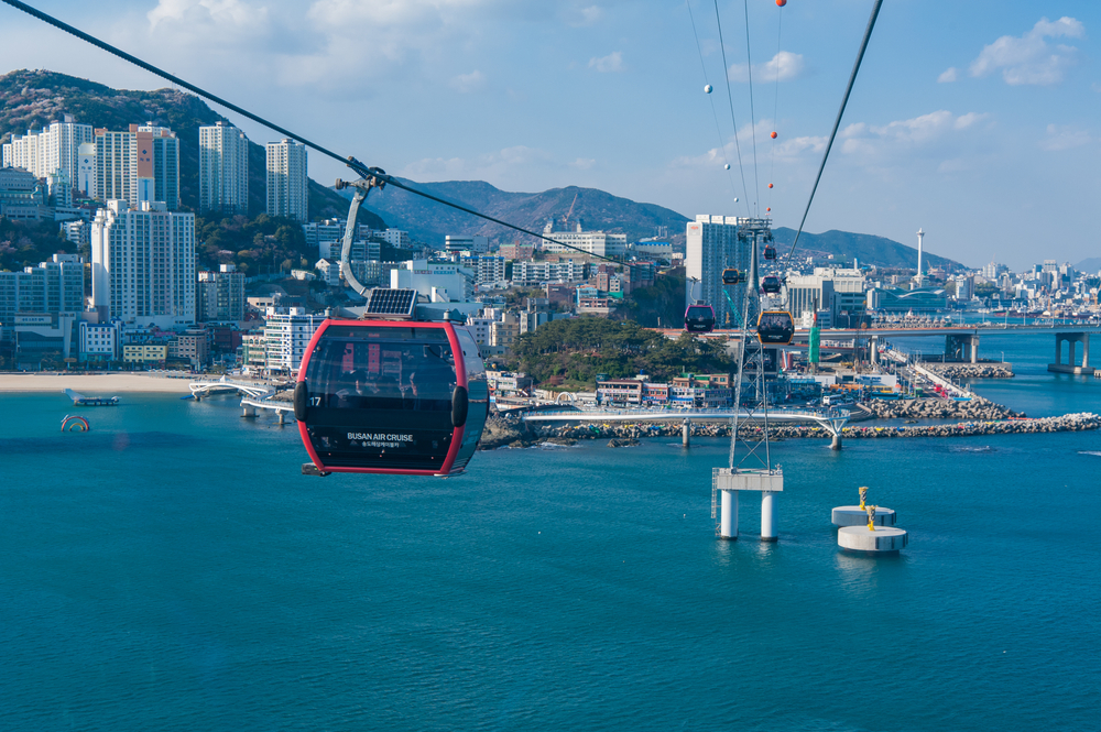 Cable cars traveling over the ocean with the city in the background, one of the best places to visit in Busan.