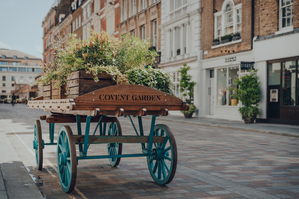 'Covent Garden" area name sign on a wooden cart with flowers on a street in Covent Garden. One of the romantic things to do in London. 