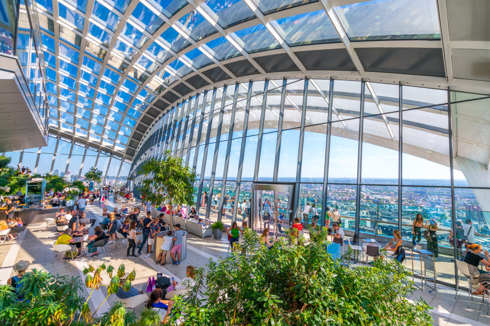 The Sky Garden at 20 Fenchurch Street is a unique public space designed by Rafael Vinoly Architects. You can see people under a glass roof with plants around. 