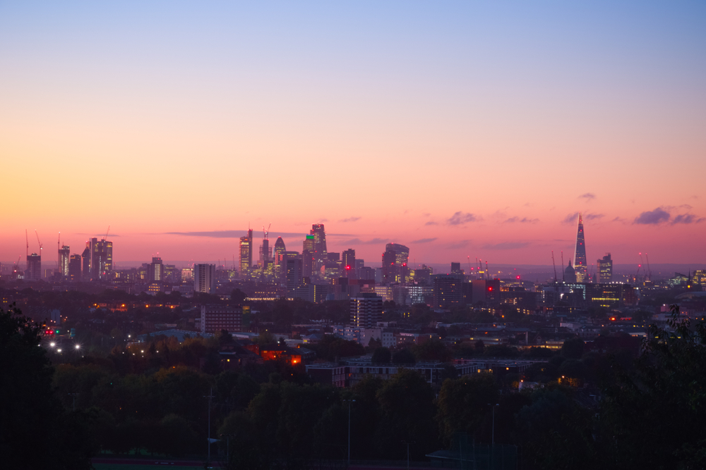 View towards London city skyline at sunrise from Parliament Hill in Hampstead Heath. One of the romantic things to do in London.