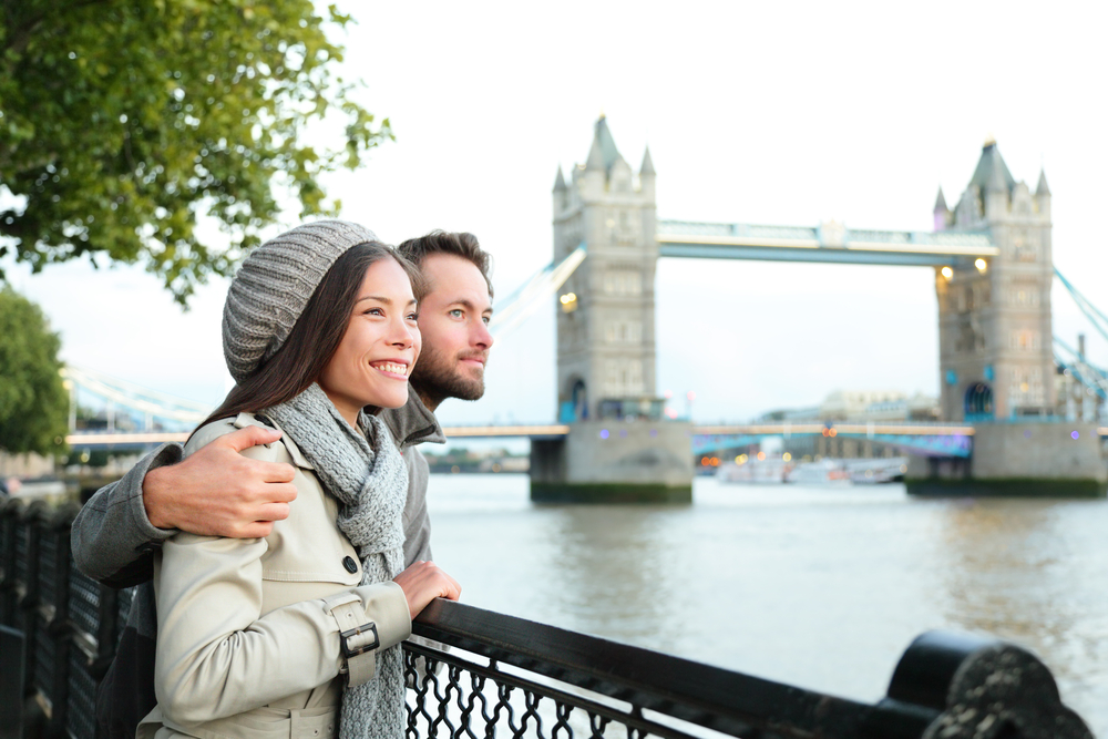 Romantic young couple enjoying view during travel. Happy couple by Tower Bridge, River Thames, London.