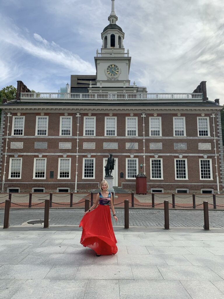Caucasian woman in front of red brick building swirling red skirt