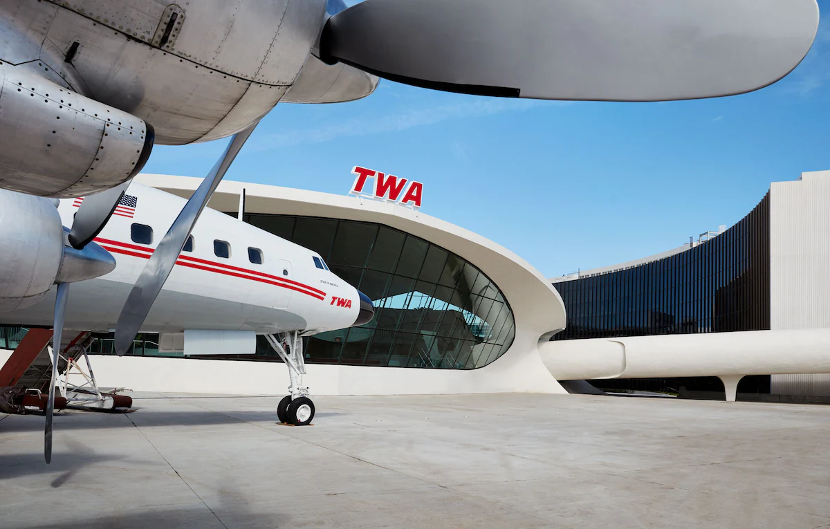 TWA letters in red with white overhang in background and plane in middle of photo