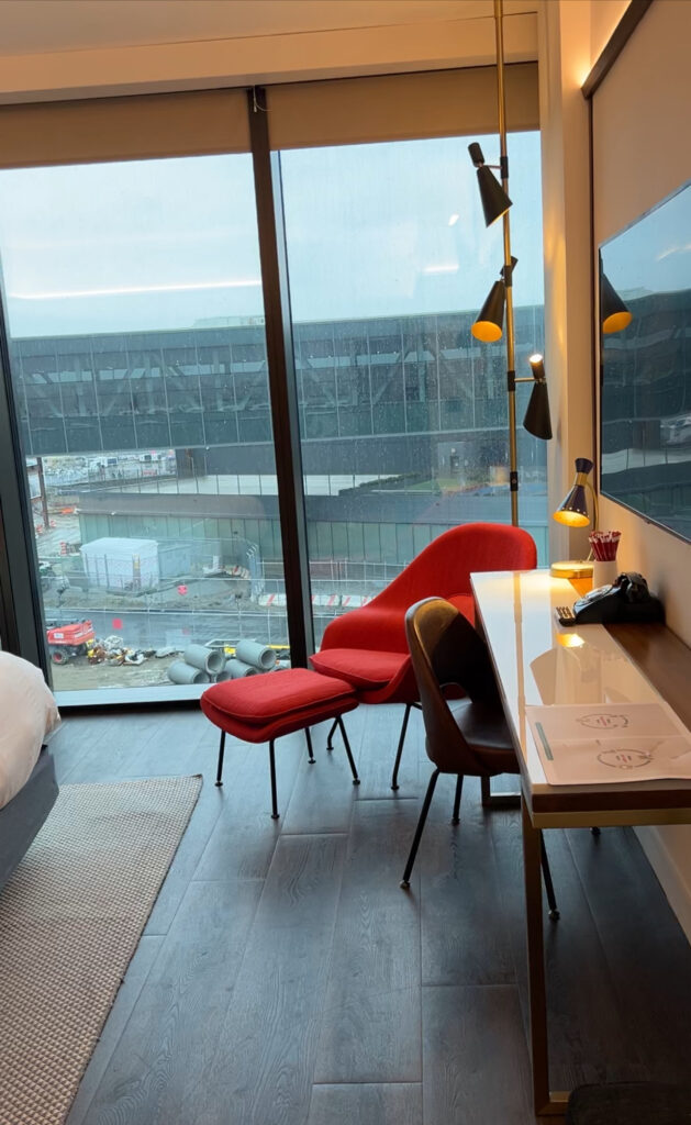 View from the hotel window at TWA hotel at JFK. You can the desk in the room and the airport out of the window. 