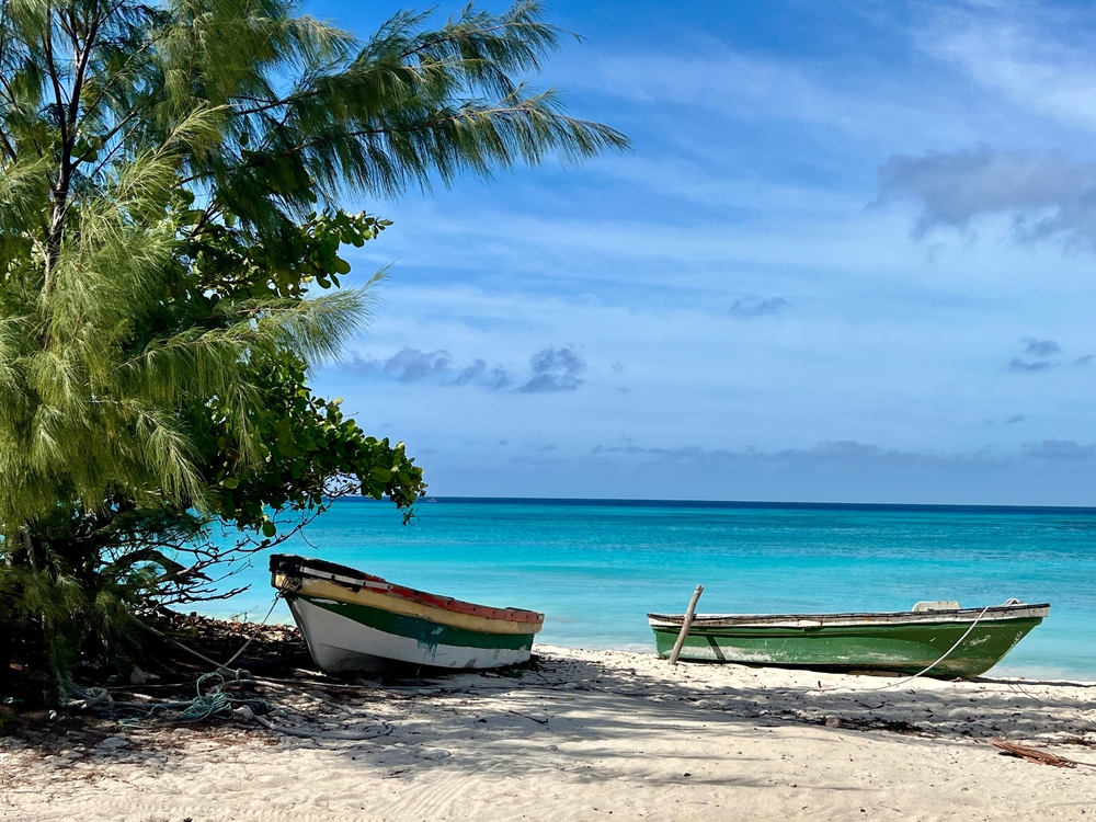 Rustic boats on the beach in Grand Turk, Turks and Caicos. Endless turquoise waters meet the horizon.. One of the 40th birthday vacation ideas