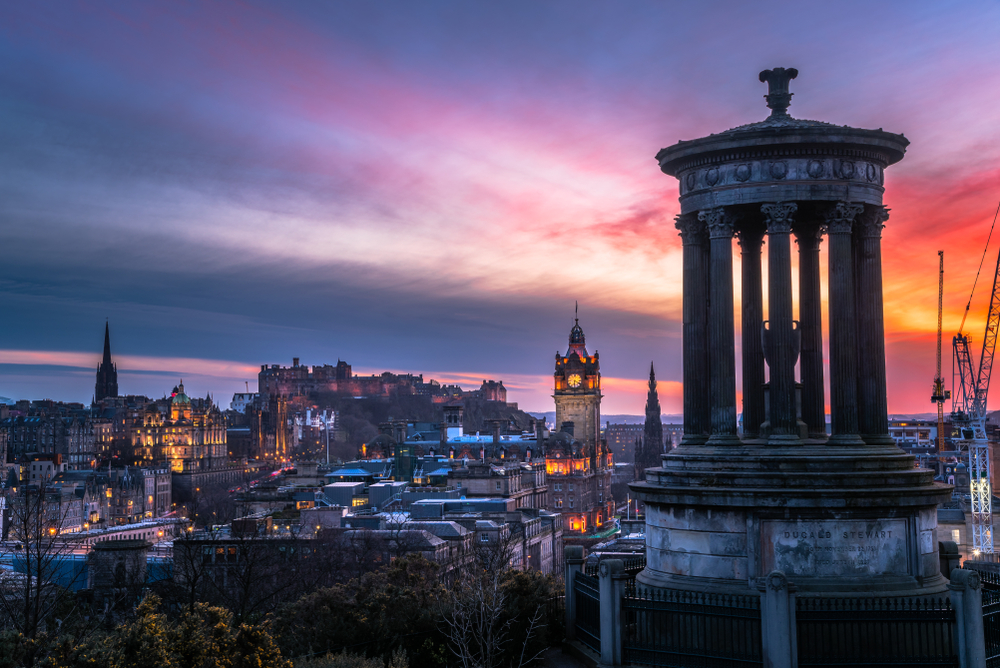 View of Edinburgh skyline at dusk in winter. A monument is in foreground.