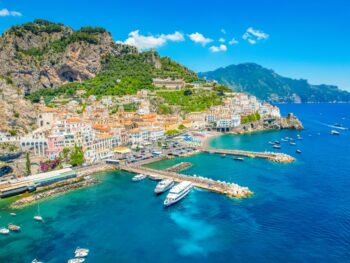 aerial view of a coastal town with boats docked and surrounded by cliffs summer in europe