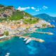 aerial view of a coastal town with boats docked and surrounded by cliffs summer in europe