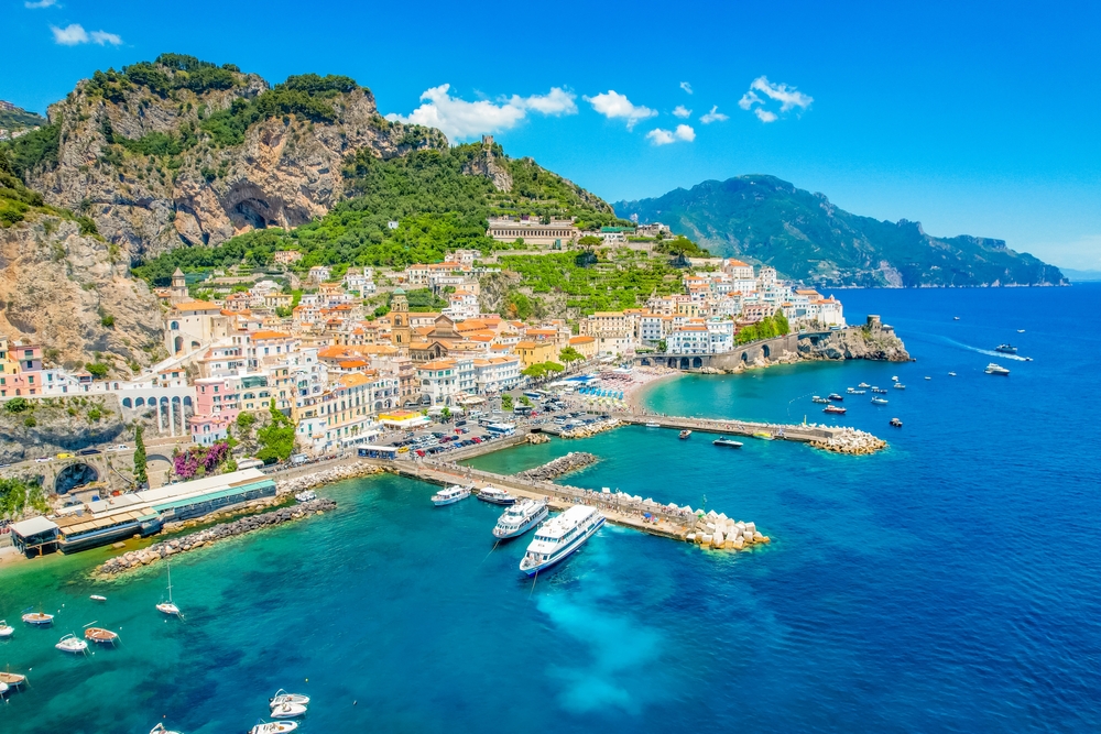 aerial view of a coastal town with boats docked and surrounded by cliffs summer in europe