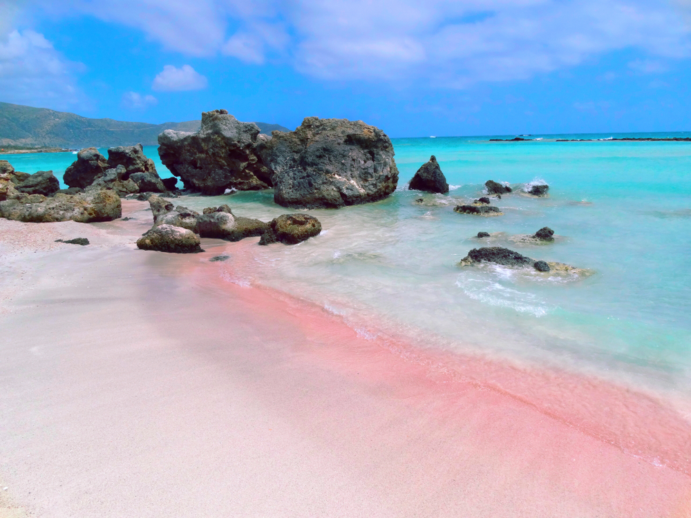 beach coast with pink sand sea landscape and mountains on Crete island