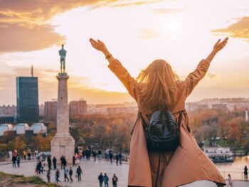 white female with arms outstretched with monument in background