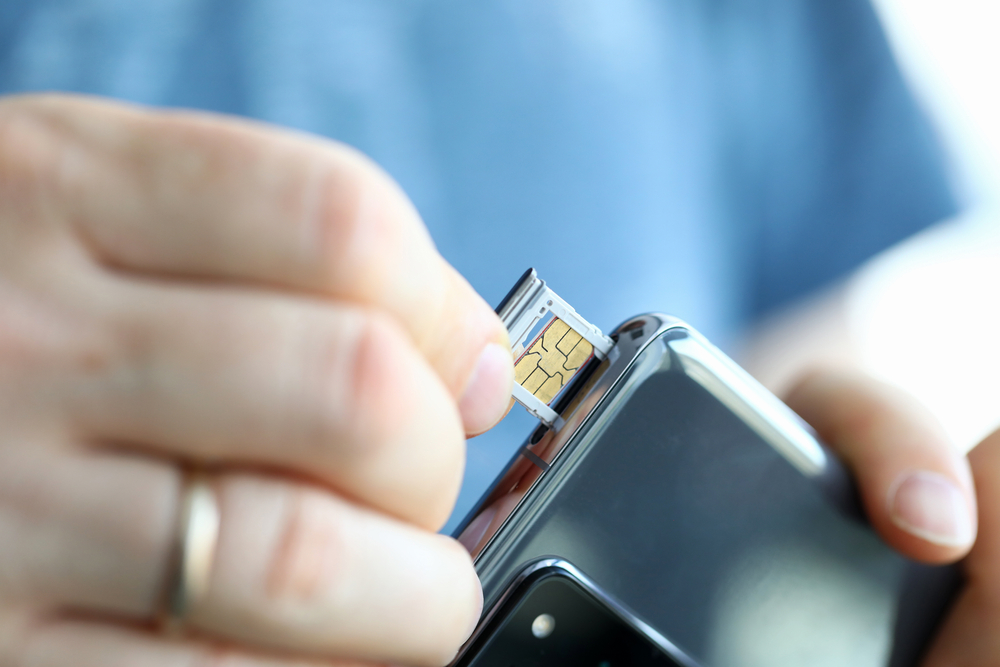 Man putting sim into phone the article is about traveling to Europe. 