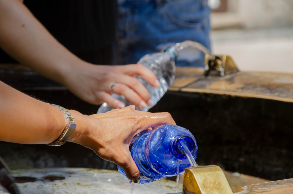 Tourists taking fresh cold water refilling their small plastic bottles from one of the public fountains in the city of verona.