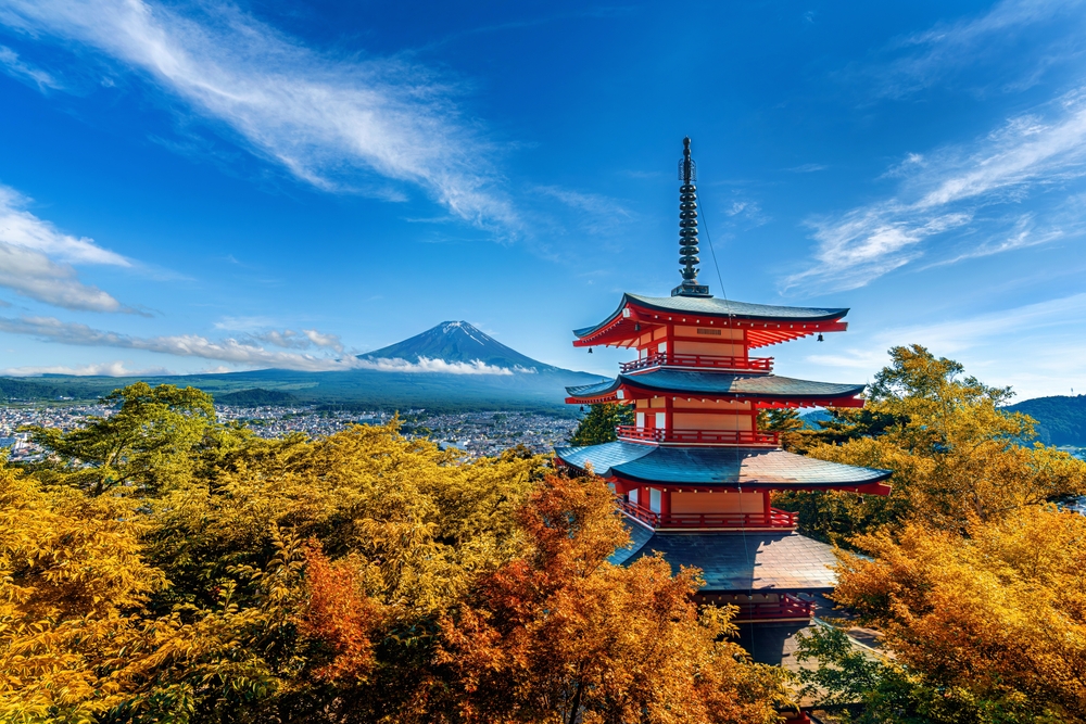 Panoramic view of a pagoda and fall foliage with Mount Fuji in the distance on a clear day in Japan, one of the best honeymoon destinations.