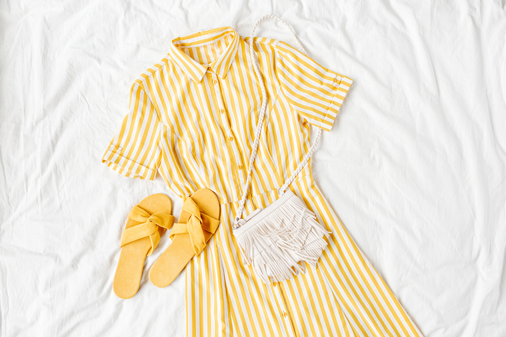 Flat lay photo of a modest yellow and white striped dress paired with yellow sandals and a purse.