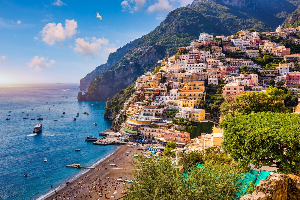 Sunset view overlooking the hillside town of Positano with a beach below.