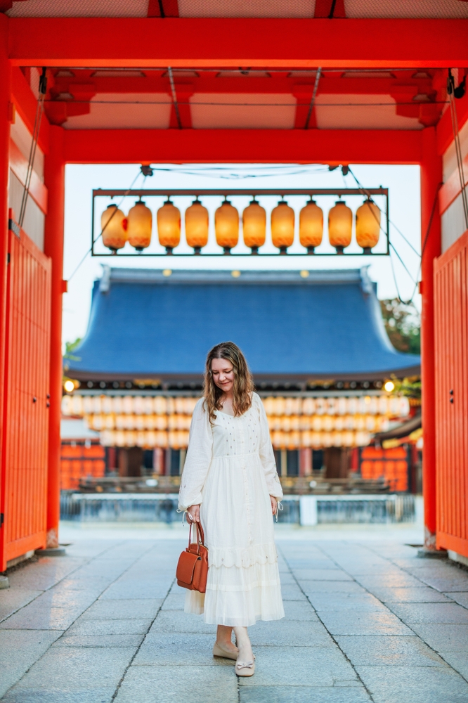 Woman standing at a temple wearing a long white dress and sandals, a great idea for What to Wear in Japan in Spring.