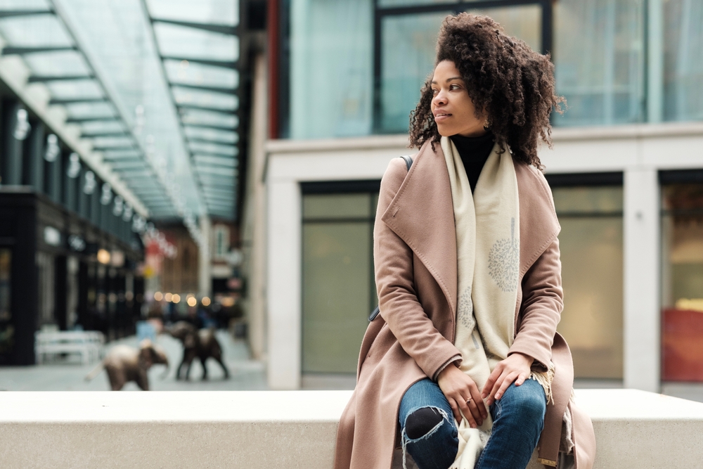 A women sat on a bench with a scarf and coat on. The article is about outfits in winter in london. 