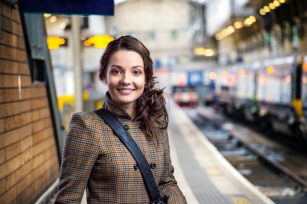 Girl in plaid coat standing at a tube station during London in winter