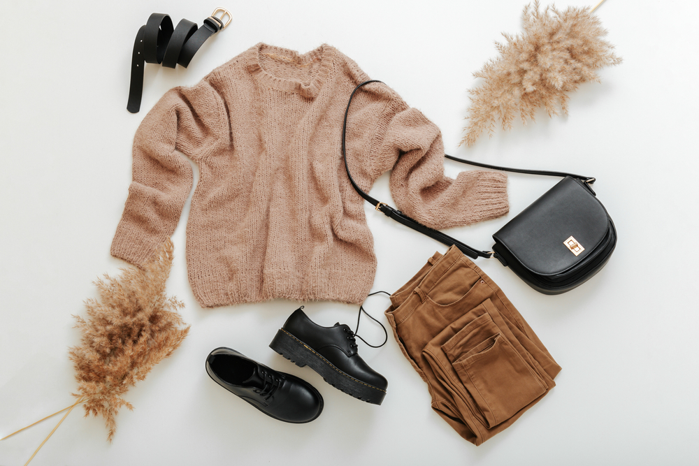 A flat lay of a winter in London outfit of brown jeans and black shoes. 