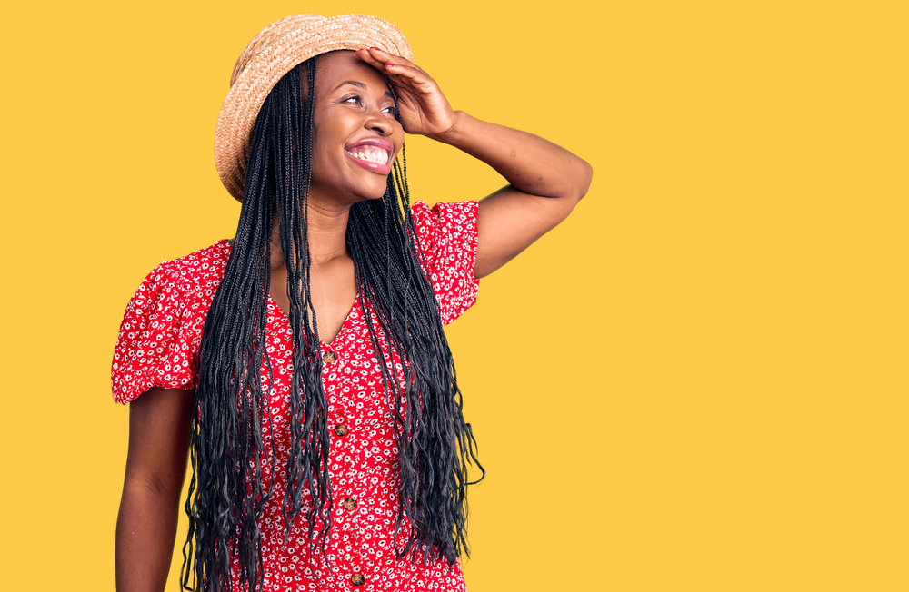 Woman in a summer dress with a hat and a red dress on a  yellow background. 