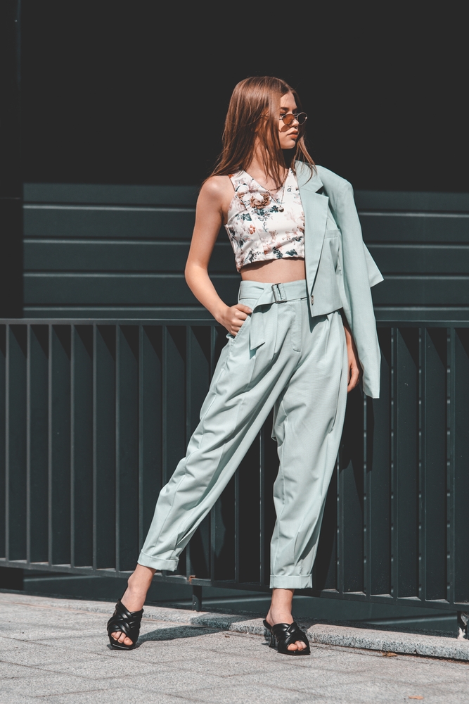 Fashion portrait of young woman wearing sunglasses, top, slingbacks, blue summer suit.