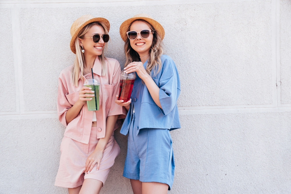 Two women wearing shorts and tops with hats. One in blue one in pink  