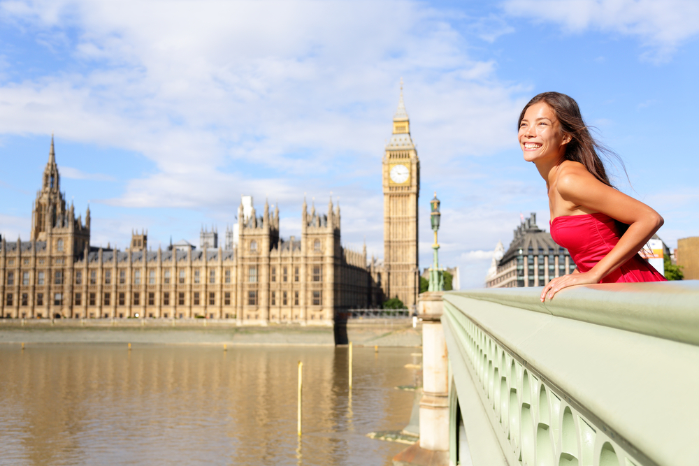 Asian woman in pink sundress leans over bridge