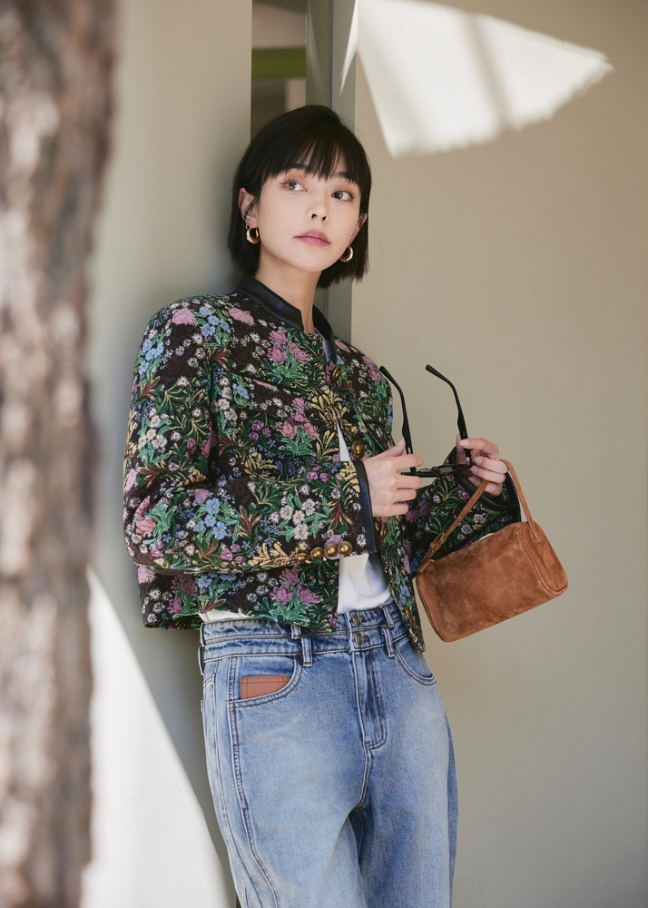 Stylish Woman Posing in a Floral Jacket with Sunglasses and a Suede Handbag. The article is about what to wearing in NYC 