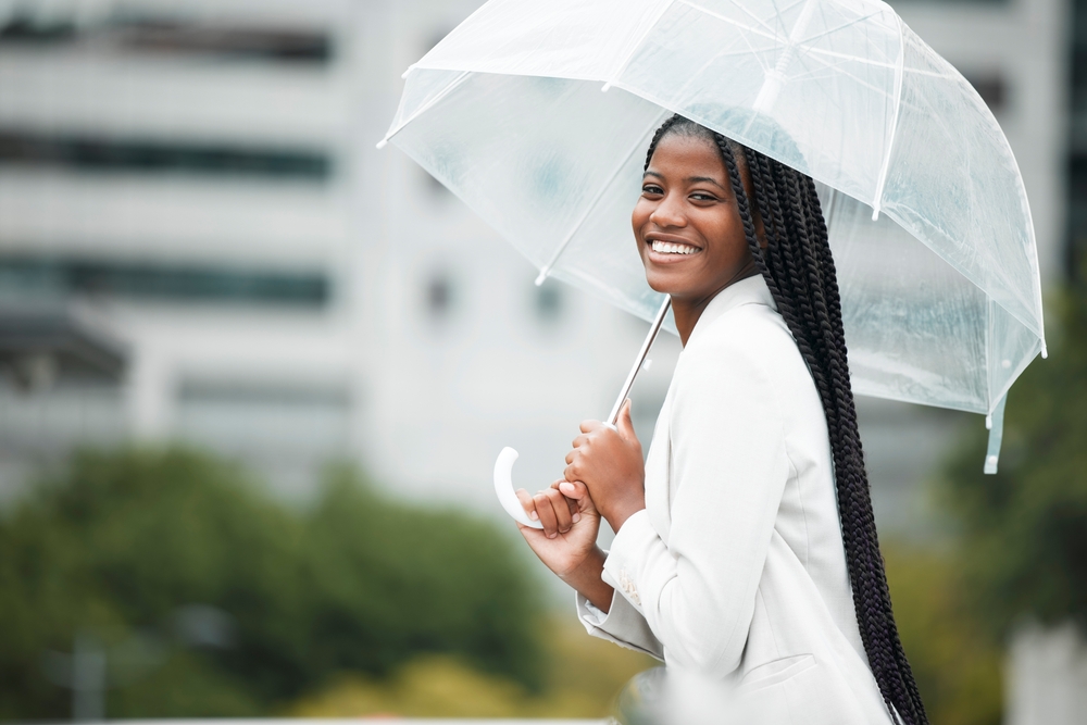 umbrella and city with a walking black woman in the street during a cold rain or wet spring day 