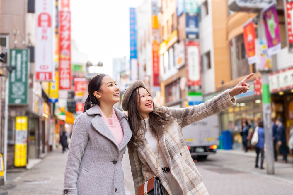 Two woman in coats walking down a shopping street in Japan.