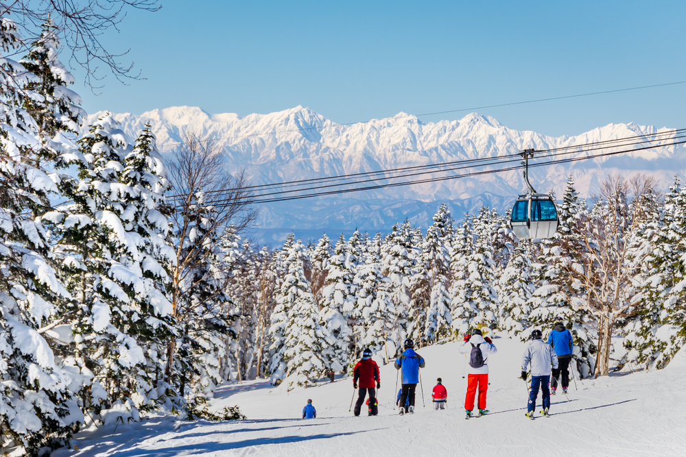 Skiers on a slope at a Japanese ski resort on a sunny day.