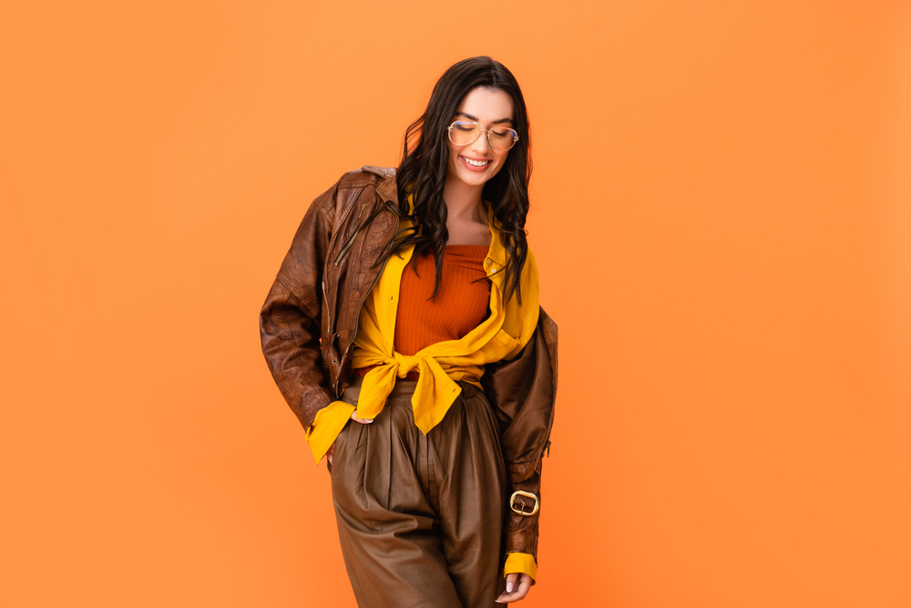 young woman in autumn outfit standing with hand in pocket and looking down