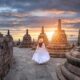 Girl in white maxi dress between the brown temple structures during the sunrise what to wear in bali